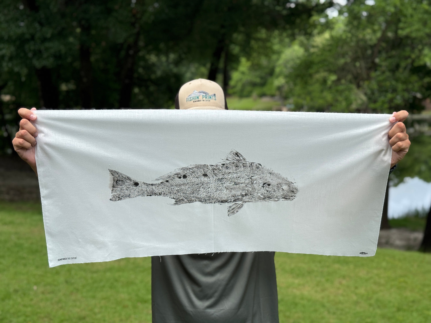 Person holding a finished product of a fishing print of a redfish outdoors