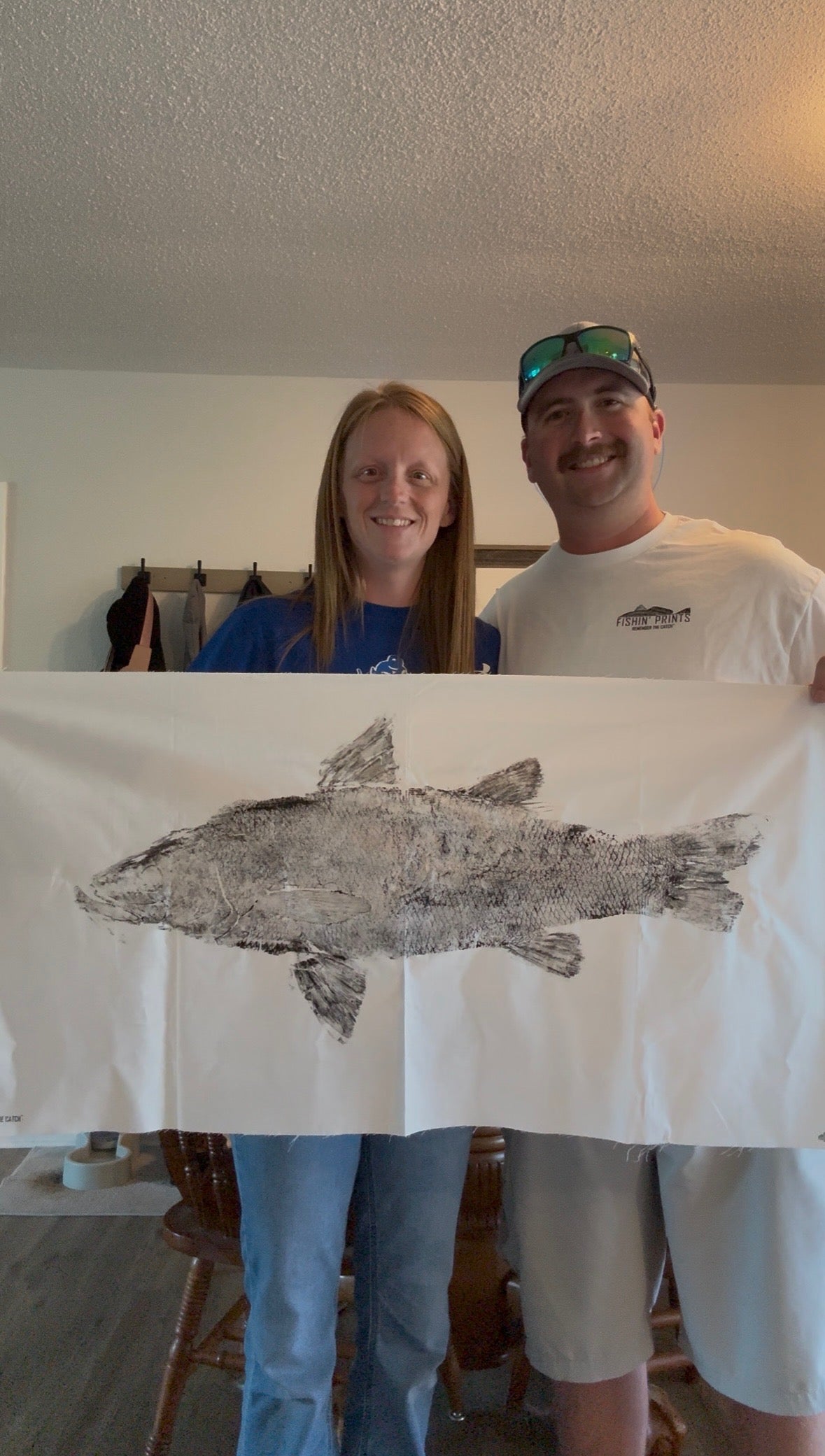 Clients holding a fishing print of a large snook. They used gytaku fish printing kiy to do it yourself.